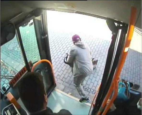 Eine Person in grauer Kleidung mit Rucksack verlässt schnell einen Bus. Der Busfahrer ist im Vordergrund sichtbar.