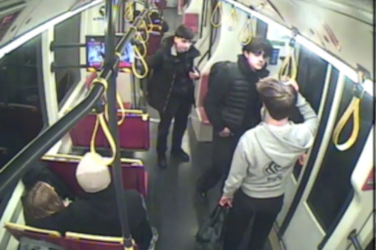 Eine Überwachungskameraaufnahme zeigt mehrere Personen in einem Tram, die sich unterhalten und stehen. Einige sitzen auf den Sitzen.