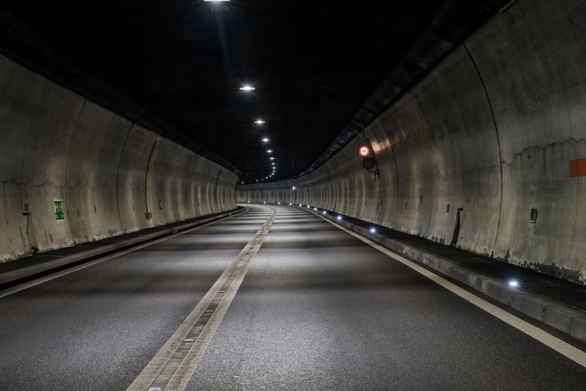 Der Tunnel ist leer und gut beleuchtet, mit einem Geschwindigkeitsbegrenzungsschild an der rechten Wand. Keine Fahrzeuge oder Personen sind sichtbar.