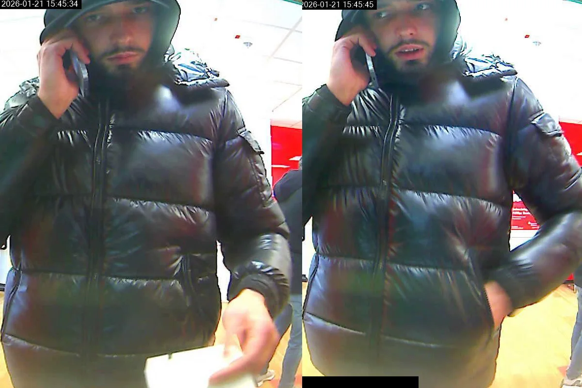 Eine Überwachungskamera zeigt einen Mann in einer schwarzen Jacke, der in einem hell erleuchteten Raum telefoniert.