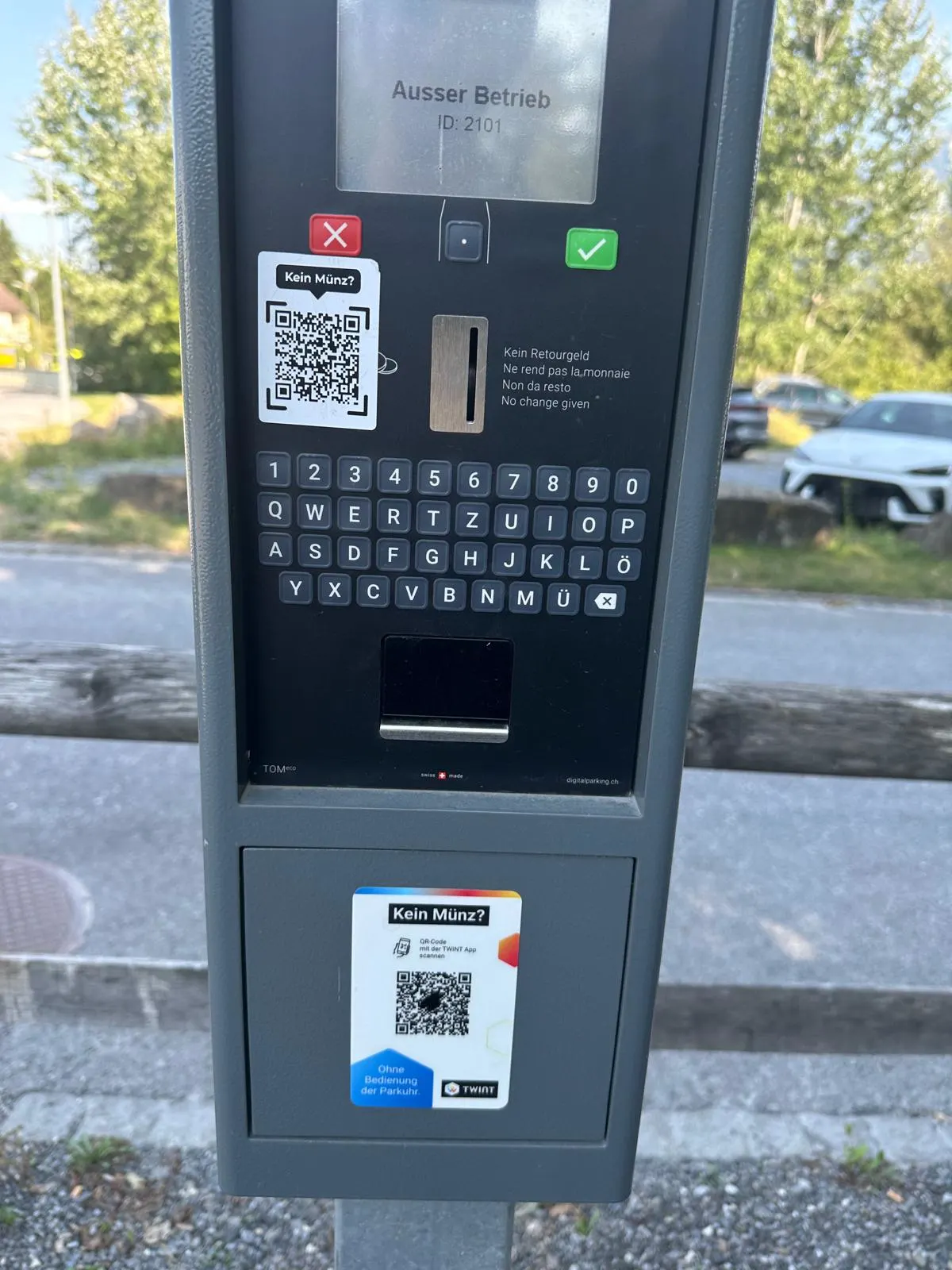 Ein Parkautomat zeigt den Hinweis 'Ausser Betrieb'. Auf dem Automat befindet sich ein QR-Code mit der Aufschrift 'Kein Münz?'.