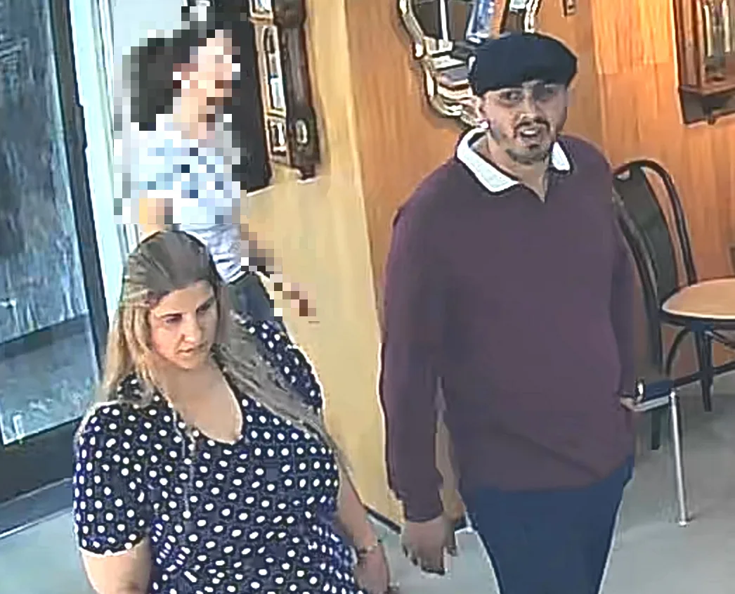 Eine Frau und ein Mann sind in einem Innenbereich auf einer Überwachungsaufnahme zu sehen. Der Hintergrund zeigt einen Tisch und Stühle.