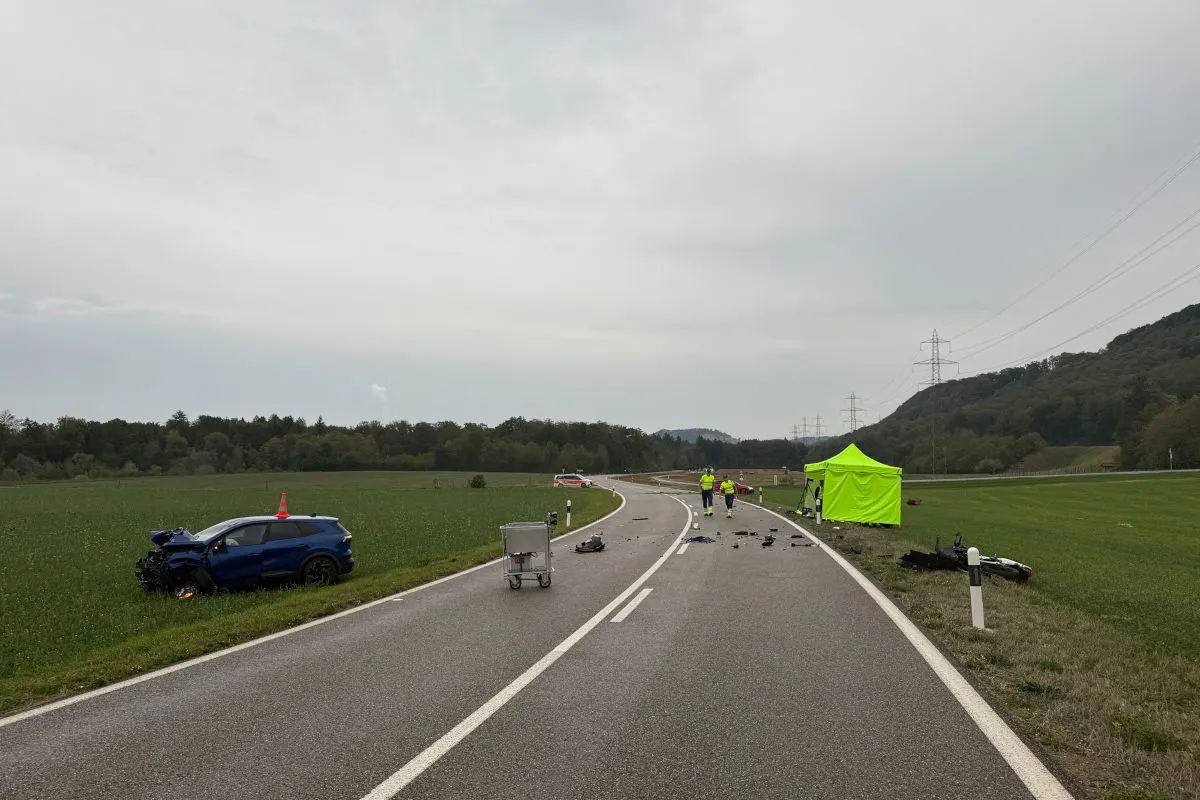 Ein blaues Auto steht schwer beschädigt im Graben neben einer Landstraße; Trümmerteile sind auf der Fahrbahn verteilt.