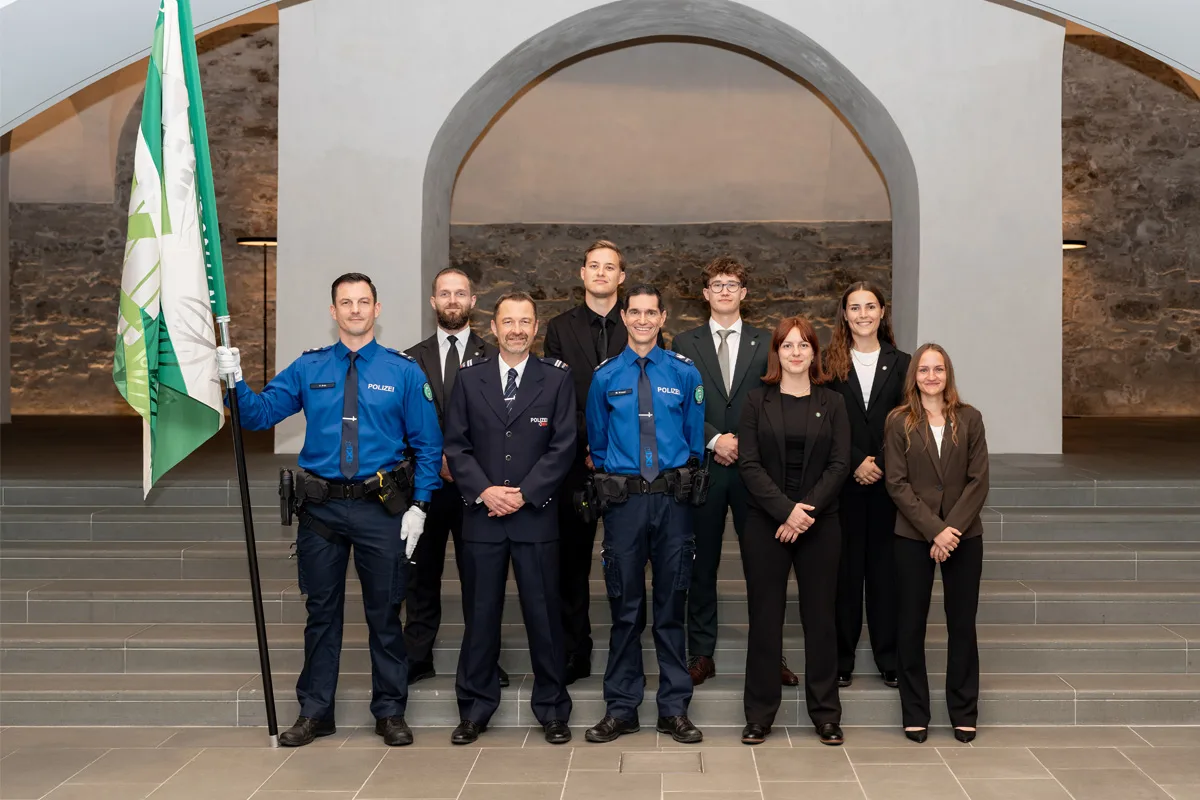 Eine Gruppe von Polizisten und Zivilpersonen steht in einem feierlichen Innenraum auf Treppen und posiert für ein Foto.