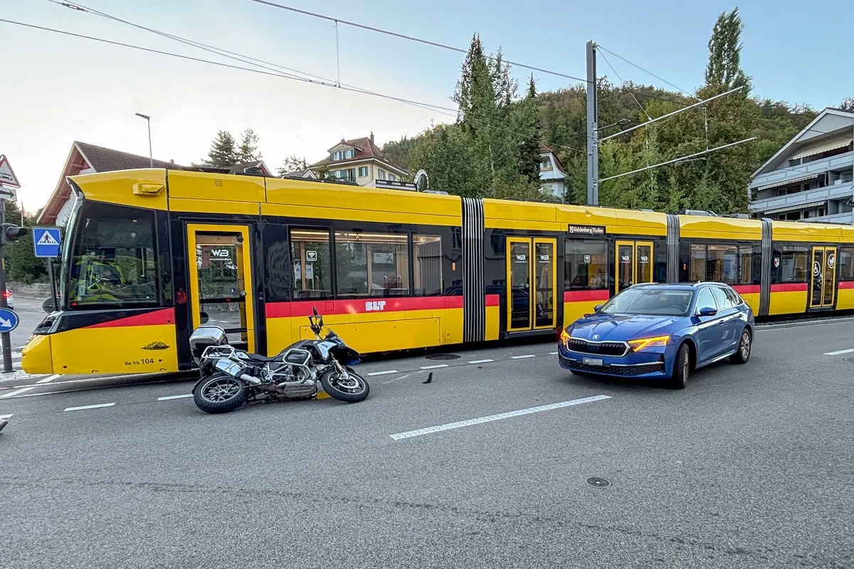 Eine gelbe Straßenbahn steht auf einer Straße. Vor ihr liegt ein umgestürztes Motorrad, daneben ein blaues Auto.