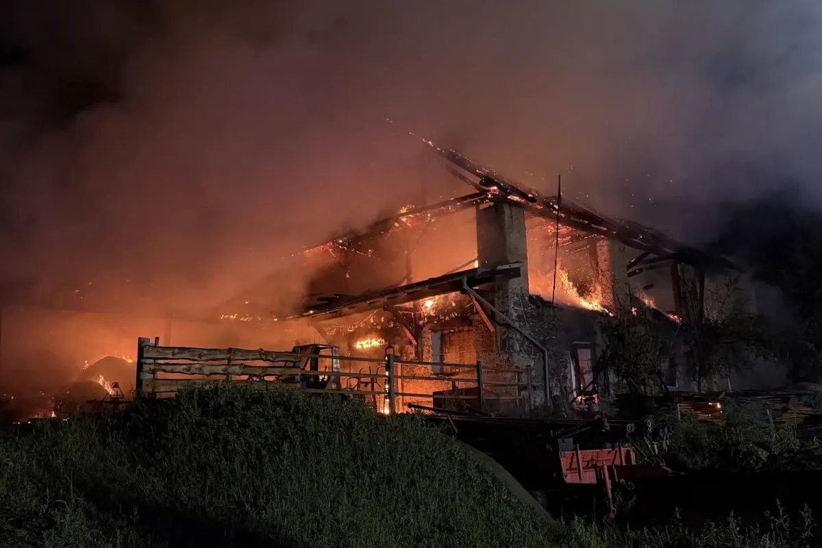 Ein Bauernhaus steht nachts in Flammen. Das Feuer hat das Dach vollständig erfasst und dicke Rauchwolken steigen auf.
