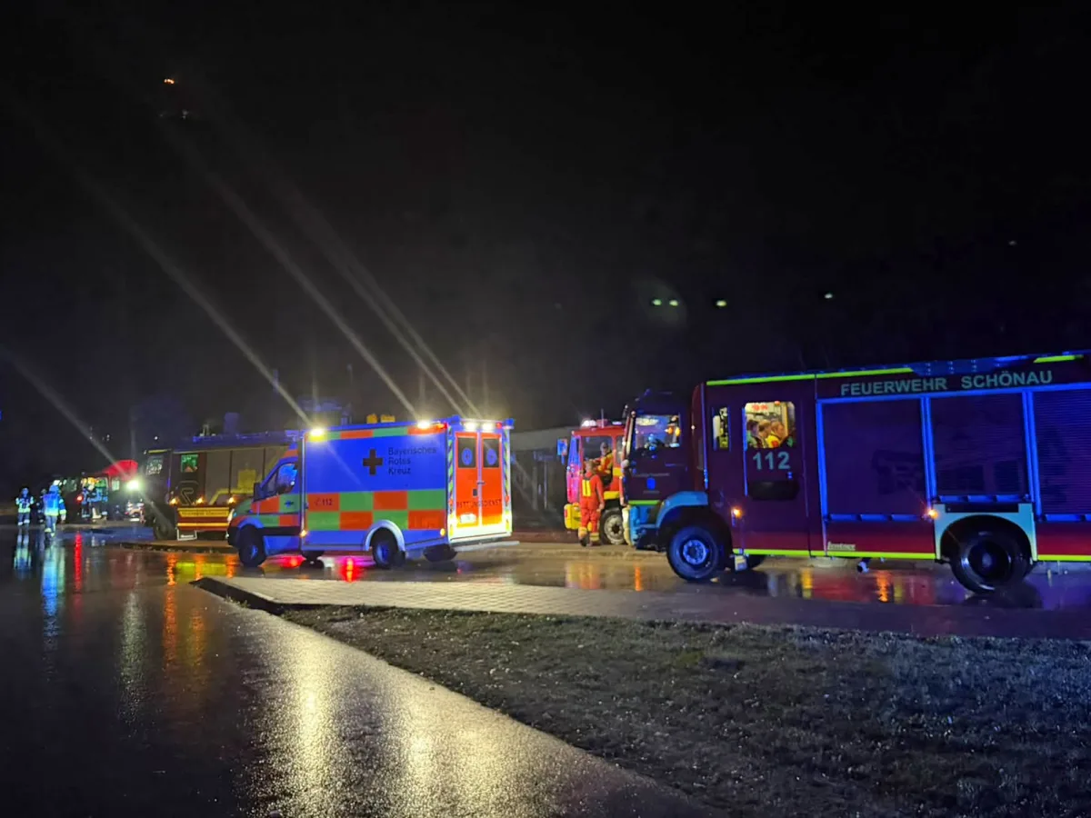 Mehrere Einsatzfahrzeuge der Feuerwehr Schönau und des Roten Kreuzes stehen nachts auf einer nassen Straße. Einsatzkräfte sind anwesend.
