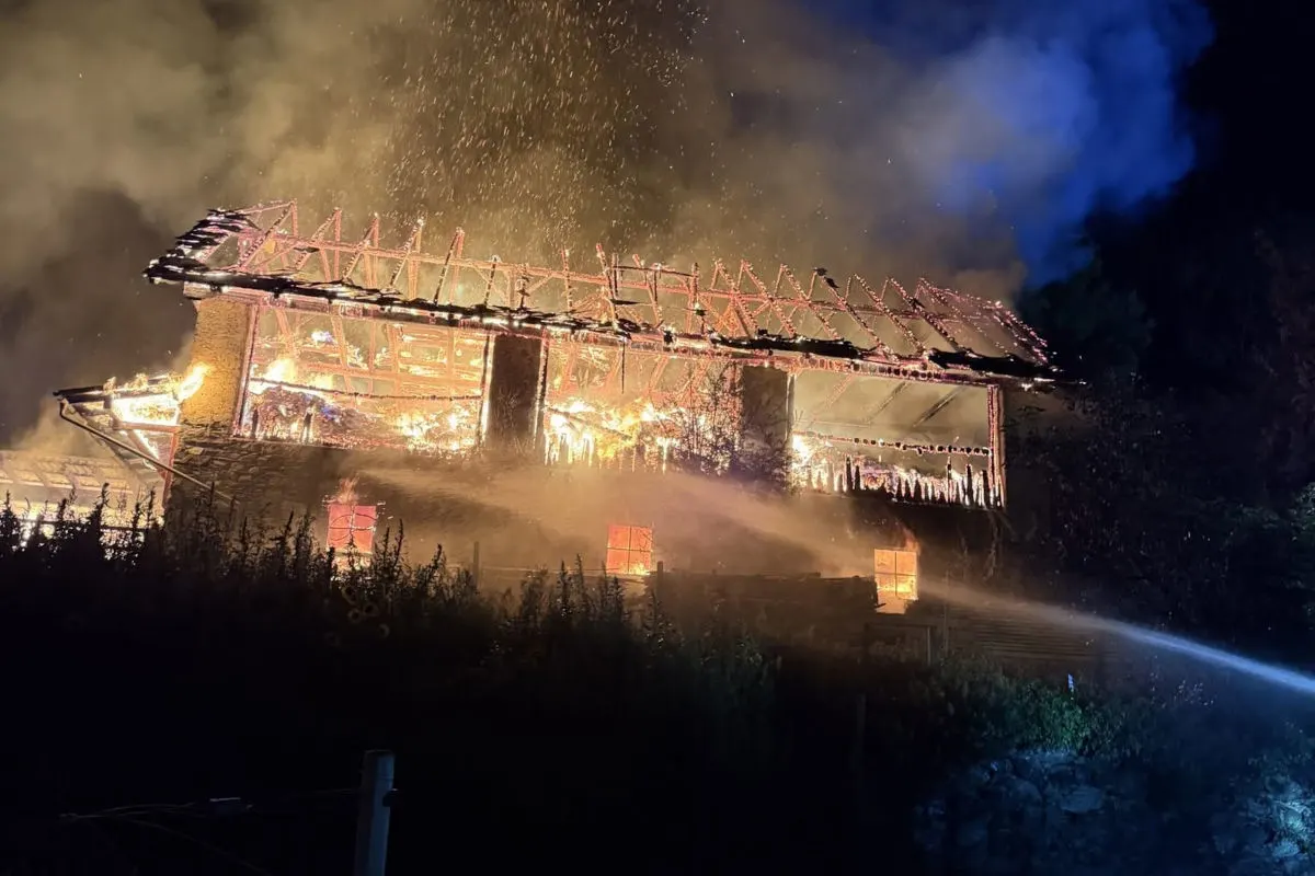 Ein großes Gebäude brennt in der Nacht. Flammen schlagen aus dem Dach und Rauch steigt auf.