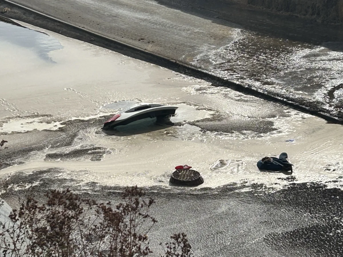Ein Auto liegt auf dem Dach in einer überfluteten Straße. Teile des Fahrzeugs ragen aus dem Wasser.