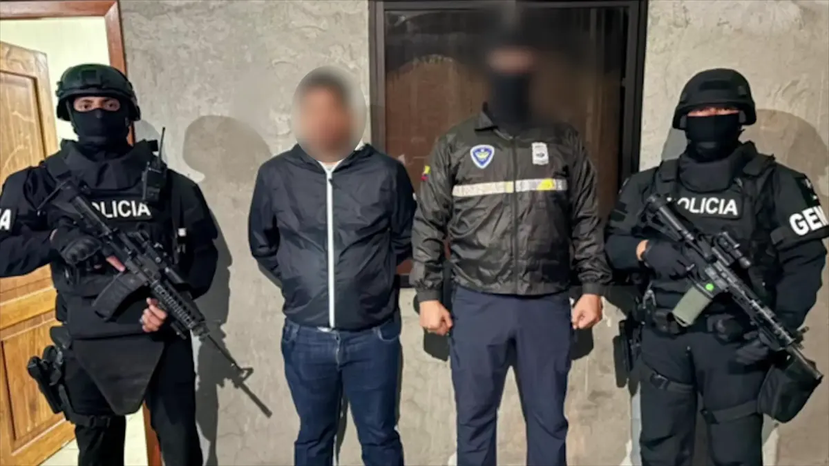 Zwei Polizisten in taktischer Ausrüstung flankieren zwei Personen, eine davon ist möglicherweise ein Verdächtiger.