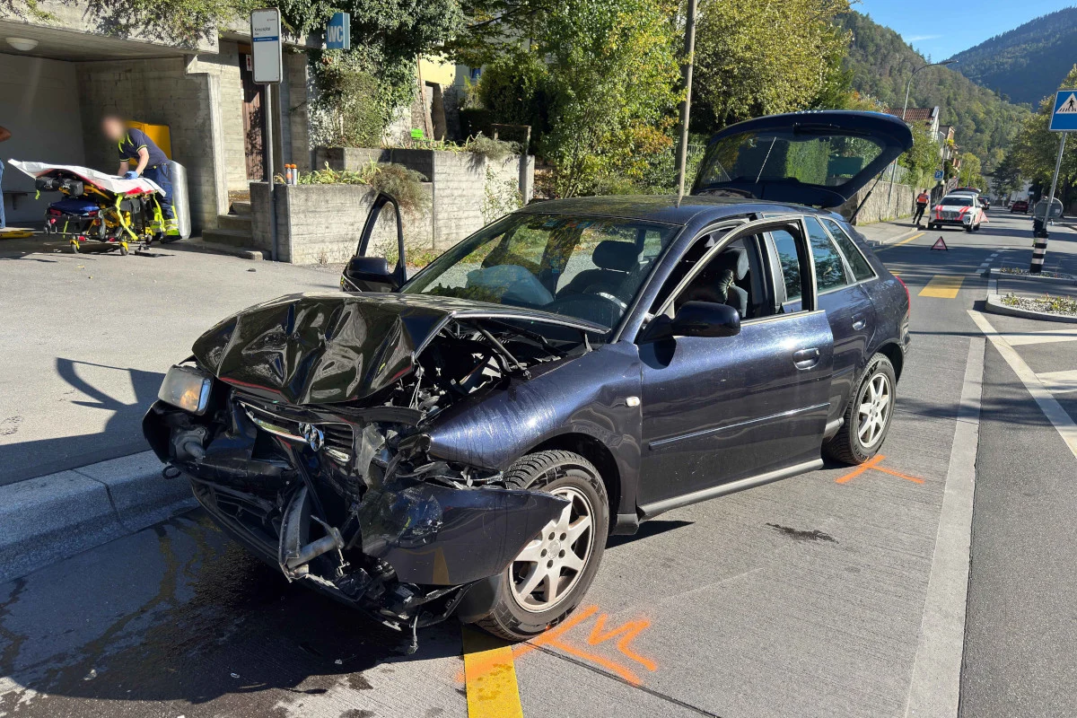 Ein Auto mit stark beschädigter Vorderseite steht auf der Straße, daneben eine Trage im Einsatz.
