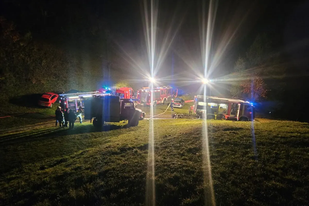 Mehrere Feuerwehrfahrzeuge stehen auf einer beleuchteten Wiese in der Nacht. Einsatzkräfte sind anwesend.