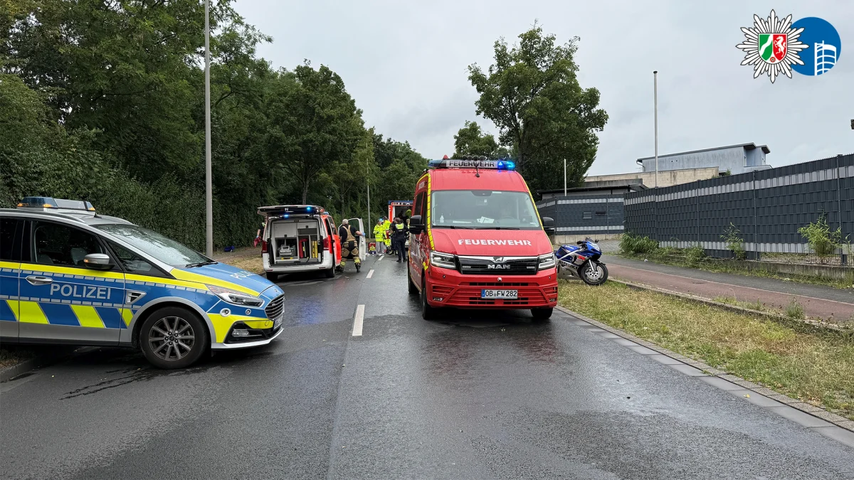 Mehrere Einsatzfahrzeuge der Polizei und Feuerwehr stehen auf einer nassen Straße. Einsatzkräfte sind im Hintergrund zu sehen.