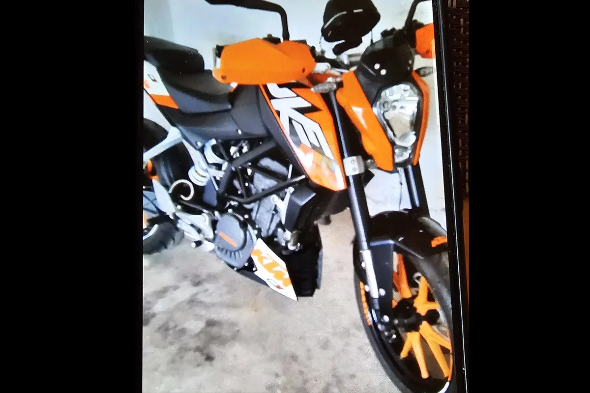 Ein auffälliges, orangefarbenes Motorrad steht in einer Garage. Es ist teils von vorne aufgenommen, mit sichtbarem Scheinwerfer und Lenker.