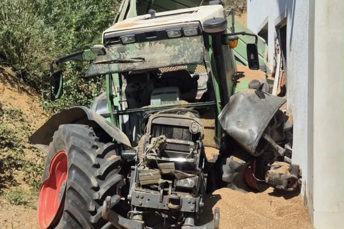 Ein grüner Traktor mit schweren Schäden an der Front steckt in einer Hauswand fest. Der Vorderteil ist eingedrückt.