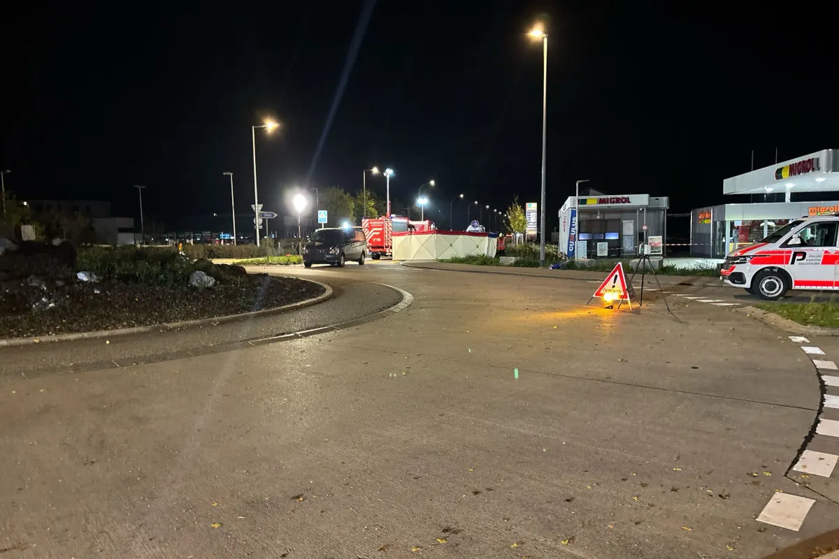 Eine nächtliche Szene zeigt eine Straßensperre auf einem Kreisverkehr. Mehrere Fahrzeuge sind im Hintergrund zu sehen, darunter ein Einsatzfahrzeug.