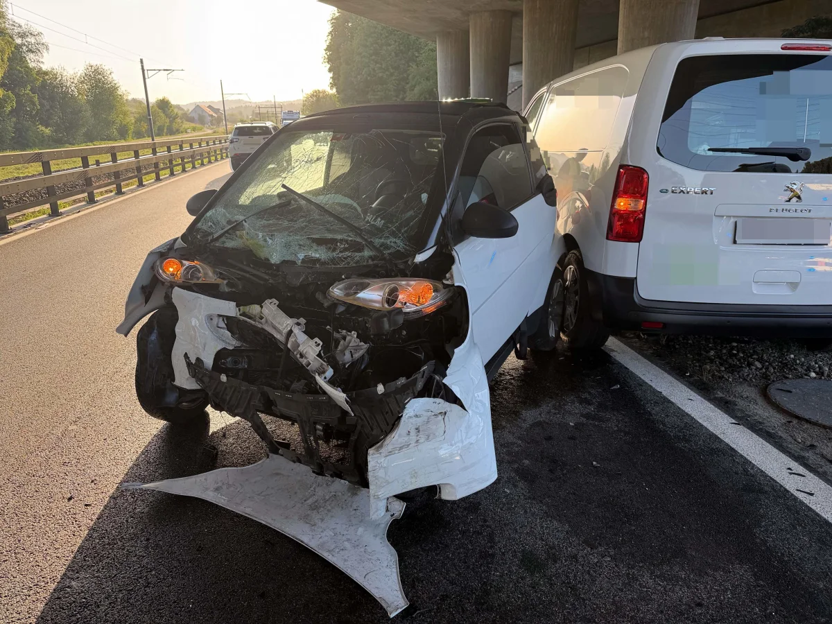 Ein stark beschädigter weißer Smart steht nach einem Unfall auf der Straße. Daneben befindet sich ein Peugeot Transporter mit leichten Beschädigungen.