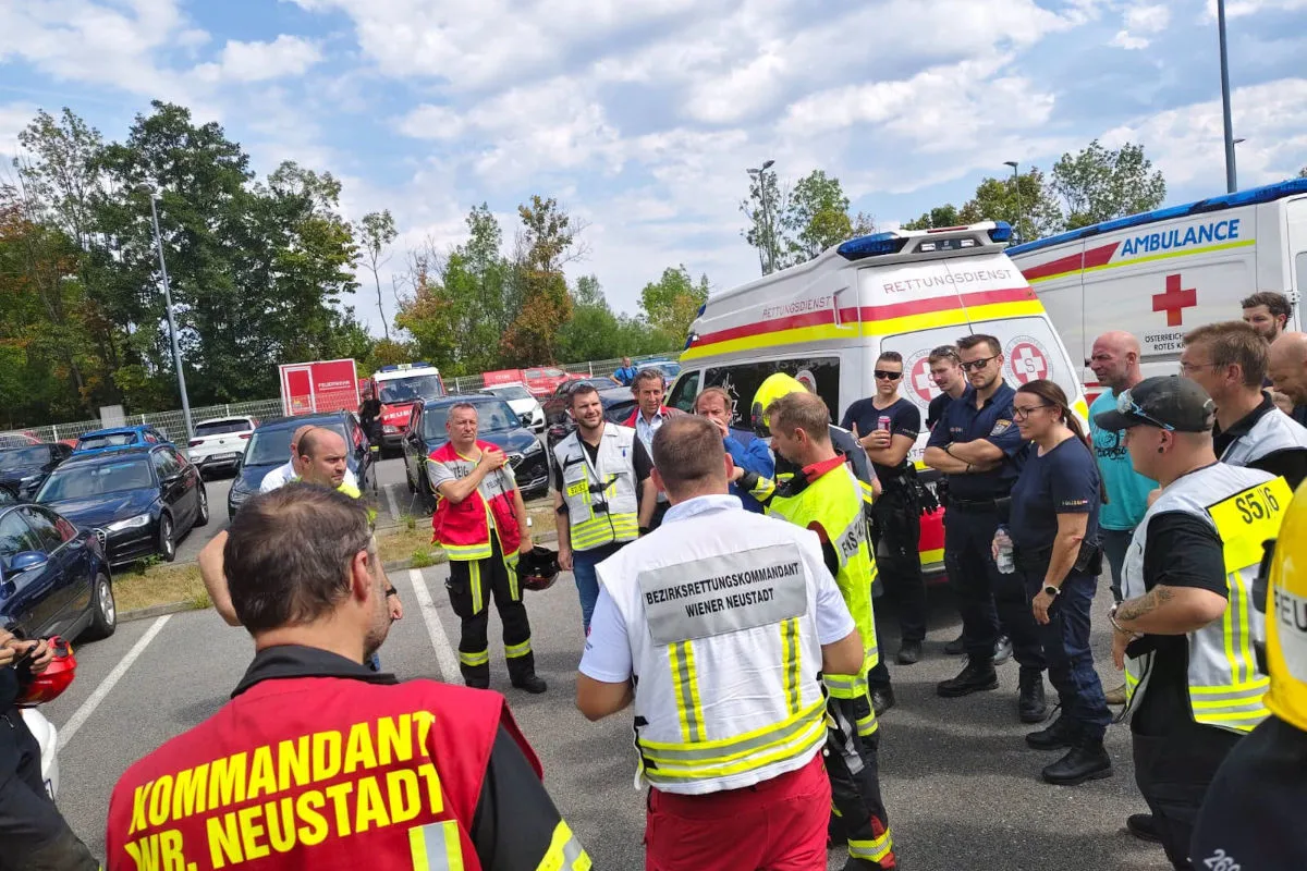 Mehrere Einsatzkräfte und andere Personen stehen in einem Kreis vor einem Rettungswagen und diskutieren miteinander.
