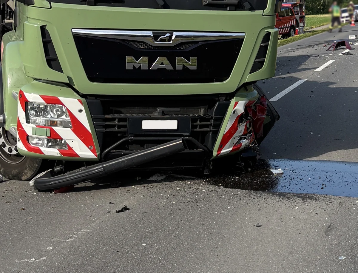 Ein grüner MAN-Lkw steht mit beschädigter Front auf einer Straße. Die Frontstoßstange ist stark verformt und es liegen Trümmer auf der Fahrbahn.