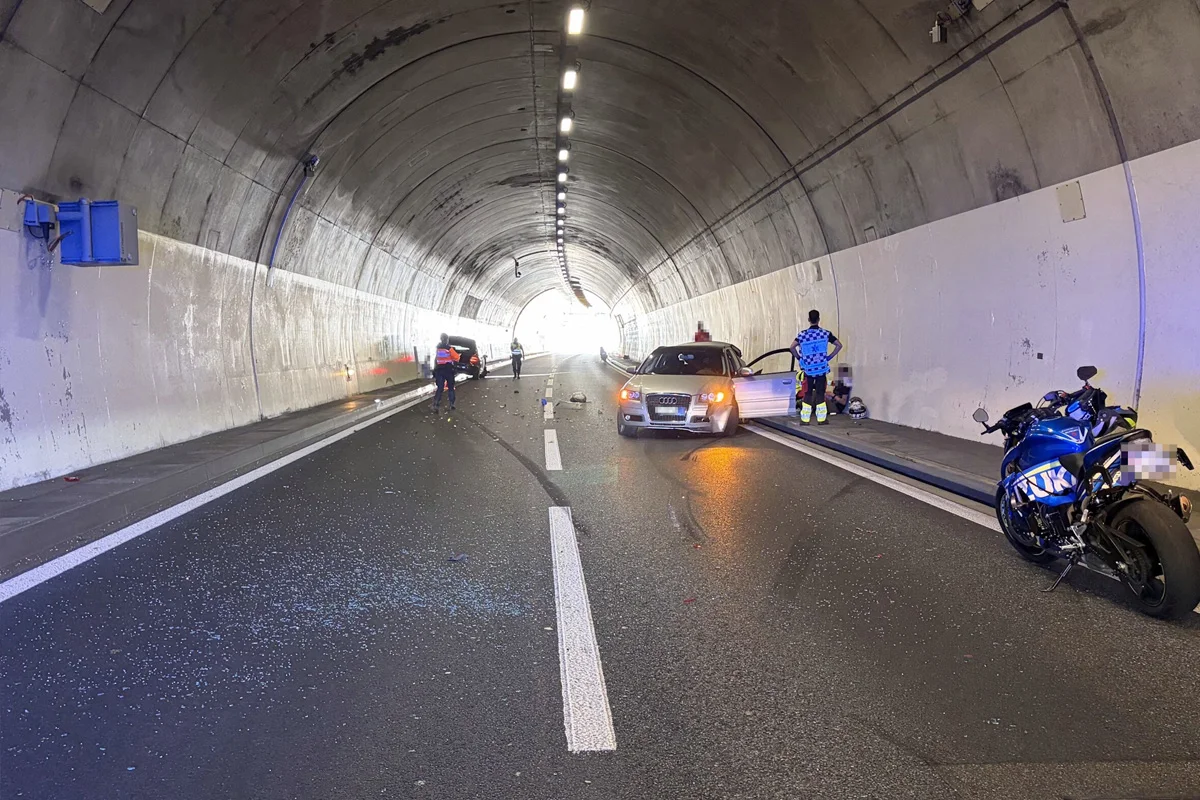 Ein Auto und ein Motorrad sind in einem Tunnel in einen Unfall verwickelt. Polizeibeamte befinden sich vor Ort zur Untersuchung.