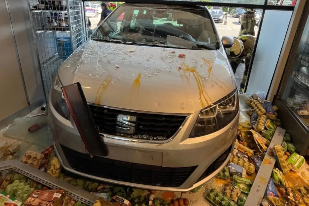 Ein Auto steht in einem Geschäft, nachdem es die Glasfront durchbrochen hat. Überall sind beschädigte Waren verstreut.