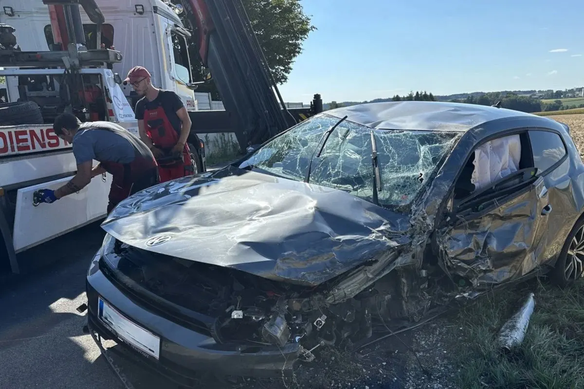 Ein stark beschädigtes Auto mit eingeschlagenen Scheiben wird von einem Abschleppdienst aufgeladen. Zwei Männer arbeiten am Abschleppfahrzeug.