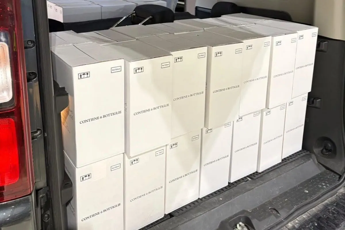 Der Kofferraum eines Fahrzeugs ist vollgepackt mit weißen Kisten, die jeweils sechs Flaschen enthalten. Die Kartons sind sauber gestapelt und zeigen Aufdrucke mit Hinweisen zur Handhabung.