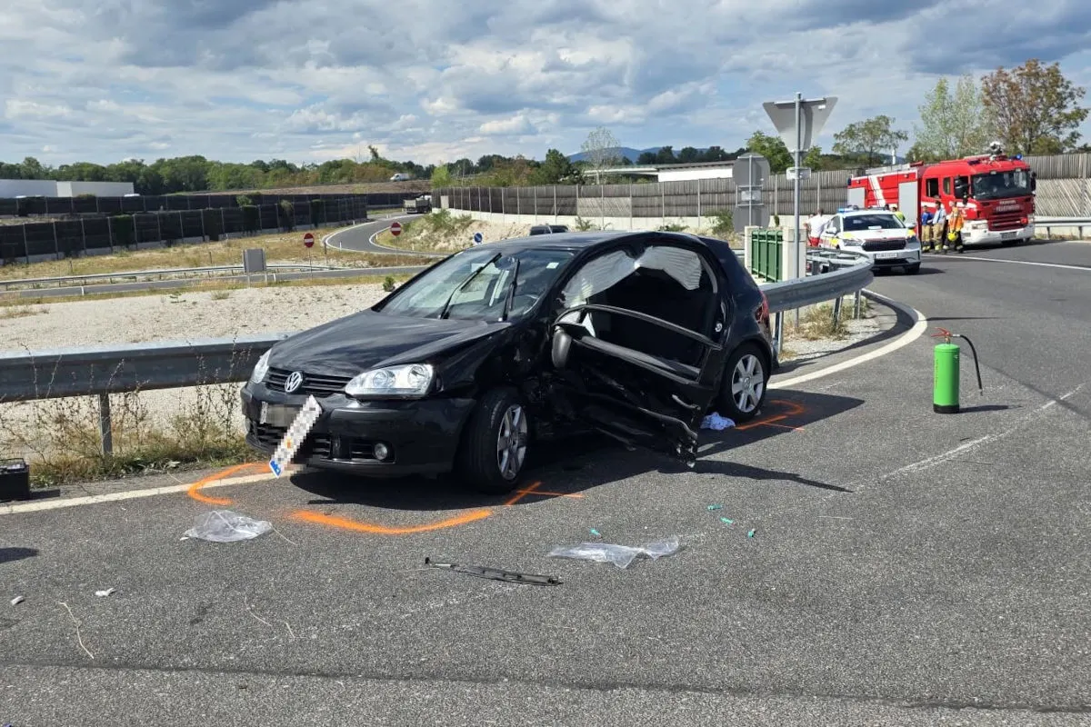 Ein schwarzer VW zeigt deutliche Unfallspuren. Feuerwehrfahrzeug und Einsatzkräfte im Hintergrund.