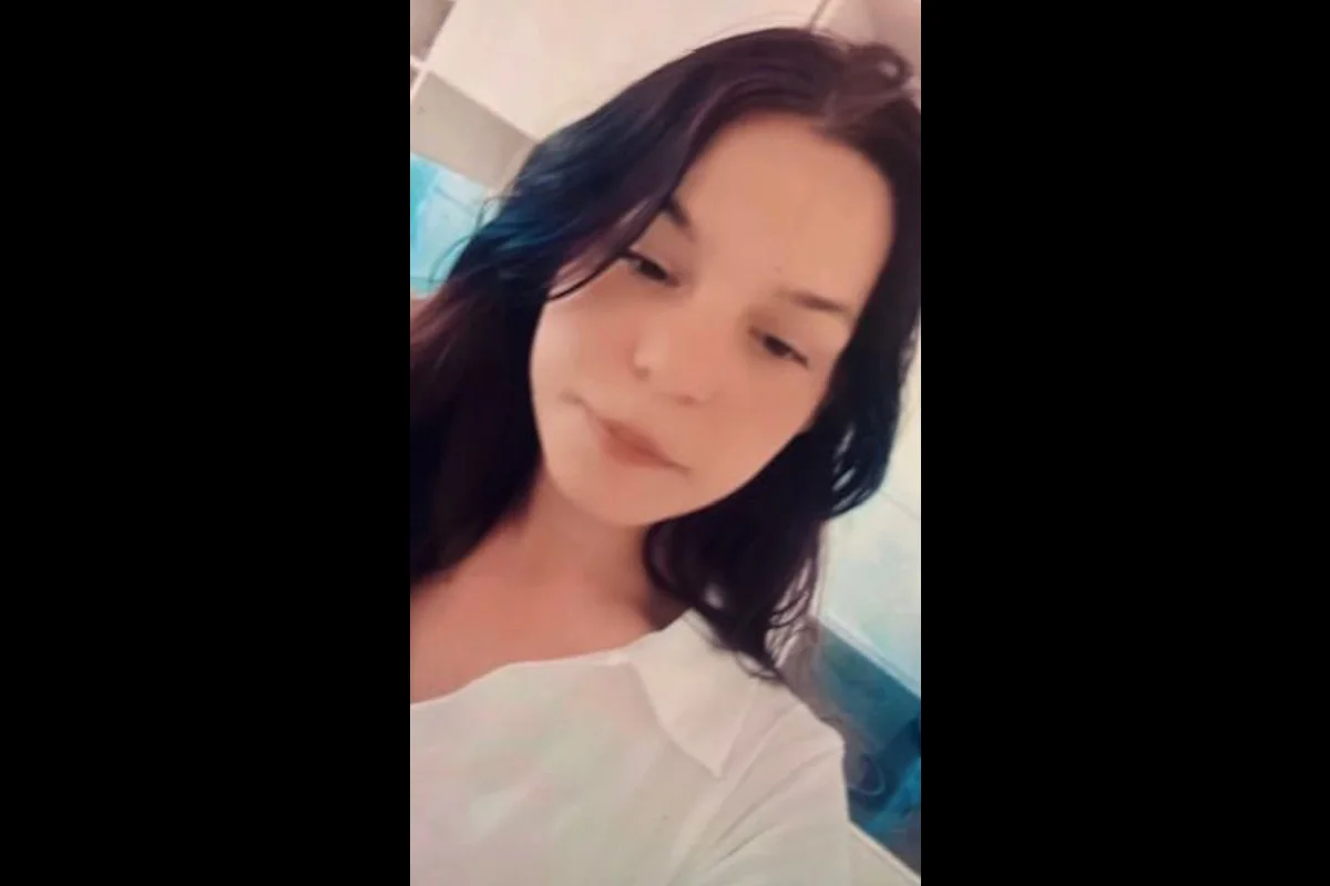 Nahaufnahme einer Frau mit dunklen Haaren in weißem Hemd vor einer unscharfen Kulisse.