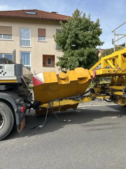 Ein Lastwagen mit einem gelben Anbaugerät steht in einer Wohnstraße. Im Hintergrund sind Wohnhäuser zu sehen.