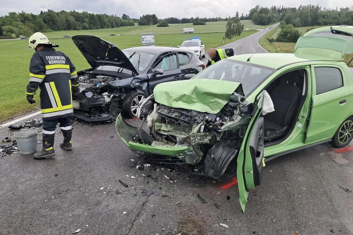 Eine grüne und eine schwarze Limousine sind nach einem schweren Unfall frontal beschädigt. Ein Feuerwehrmann ist vor Ort, um den Schaden zu begutachten.