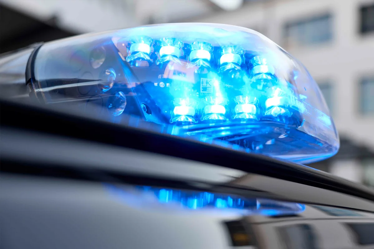 Das Bild zeigt ein leuchtendes, blaues Polizeilicht auf einem Fahrzeug. Das Licht ist in Nahaufnahme fotografiert, was die Helligkeit und Details der einzelnen Lampen hervorhebt.