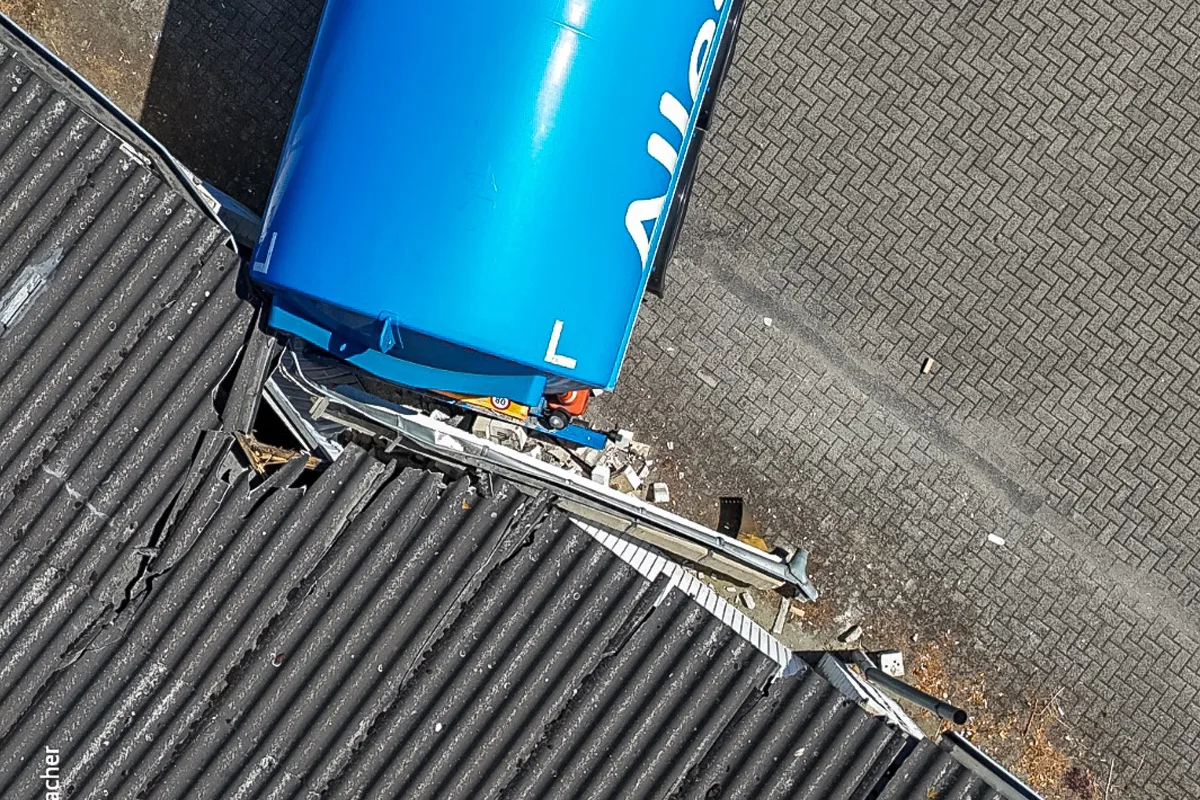 Ein blauer Tankwagen ist in ein Dach gefahren, wodurch erheblicher Schaden entstanden ist. Die Szene zeigt die Kollision von oben.