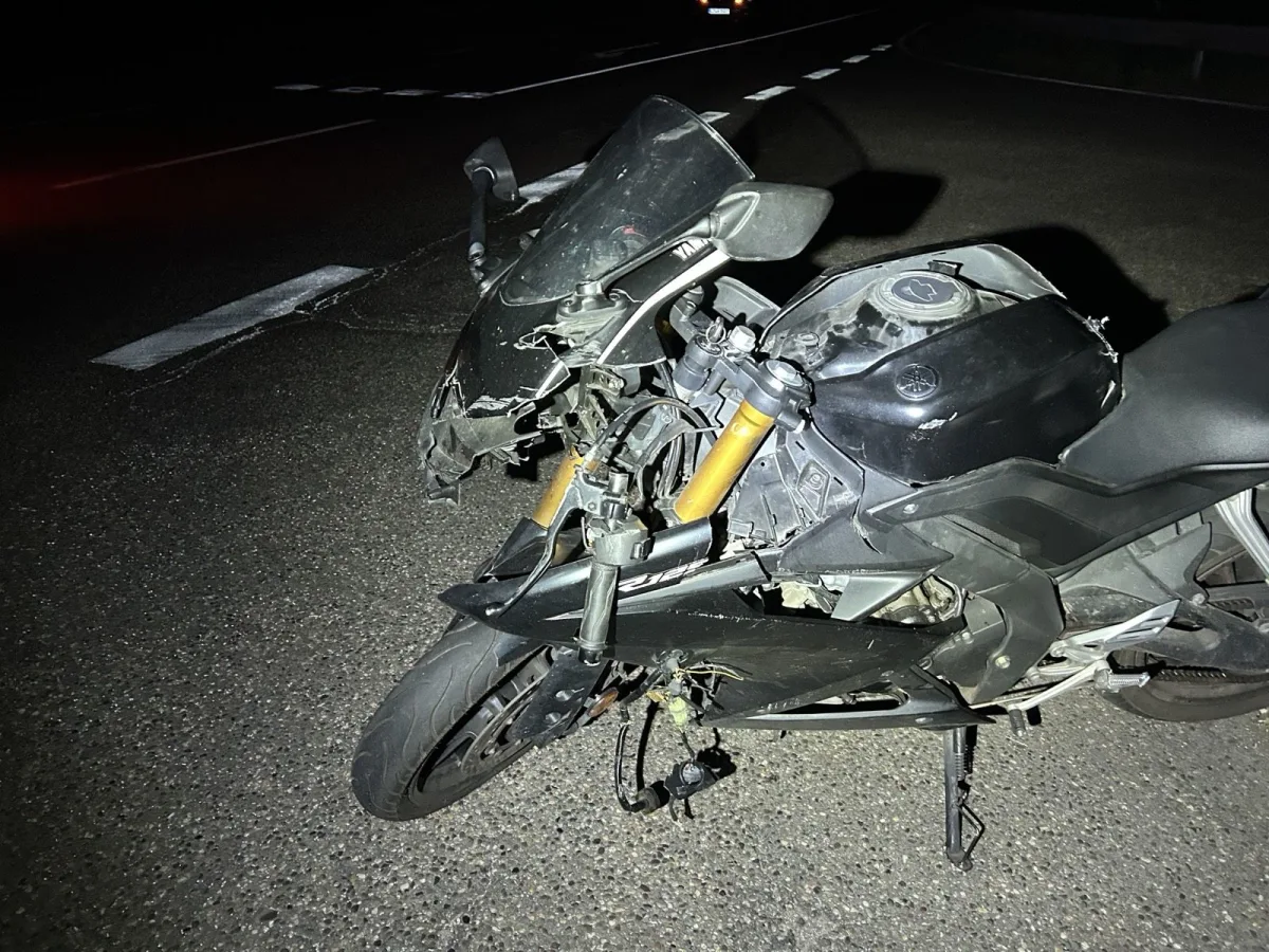Ein beschädigtes Motorrad liegt bei Nacht auf einer dunklen Straße. Die Front des Motorrads ist stark beschädigt.