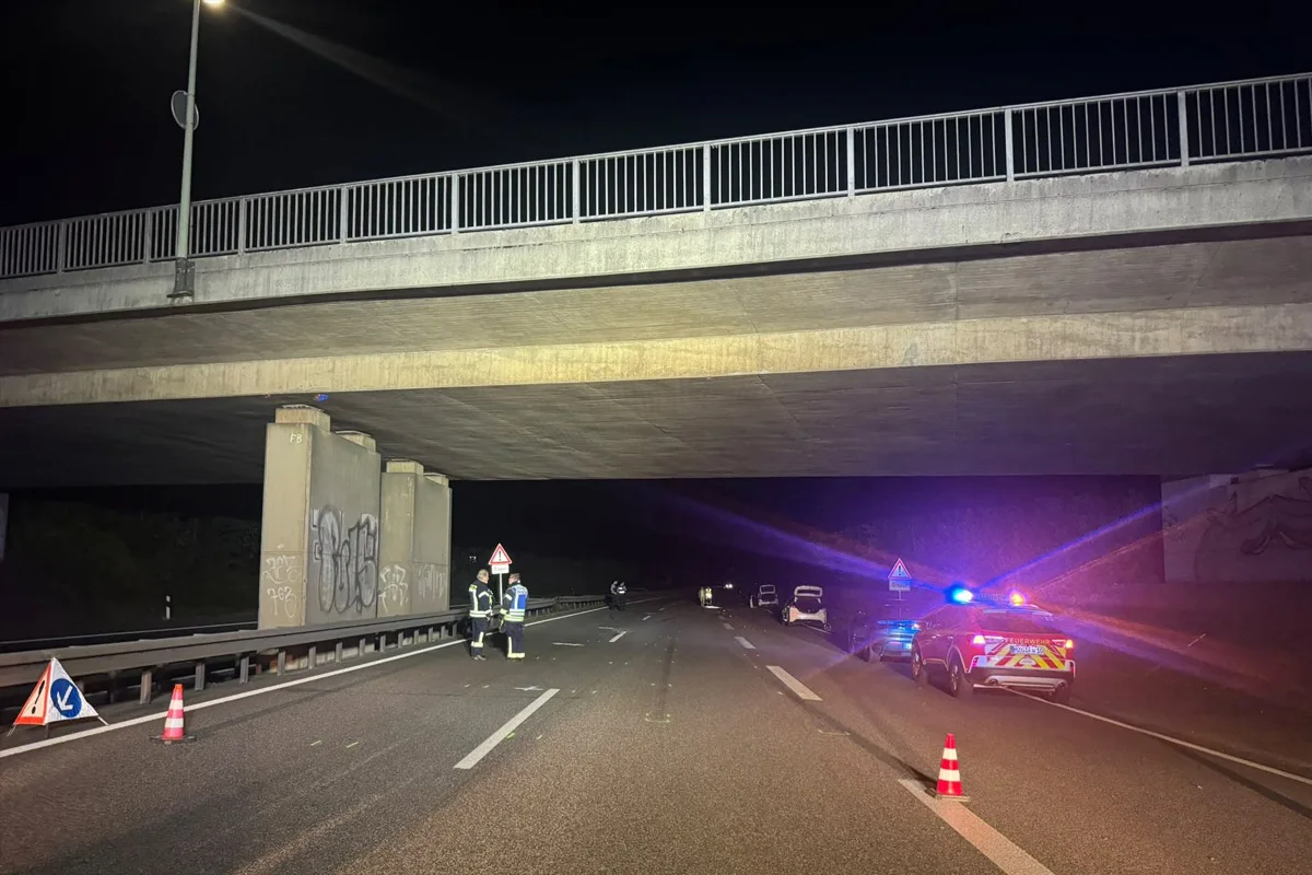 Bei Nacht sind Polizeiautos mit eingeschaltetem Blaulicht unter einer Autobahnbrücke zu sehen, die Straße ist gesperrt.