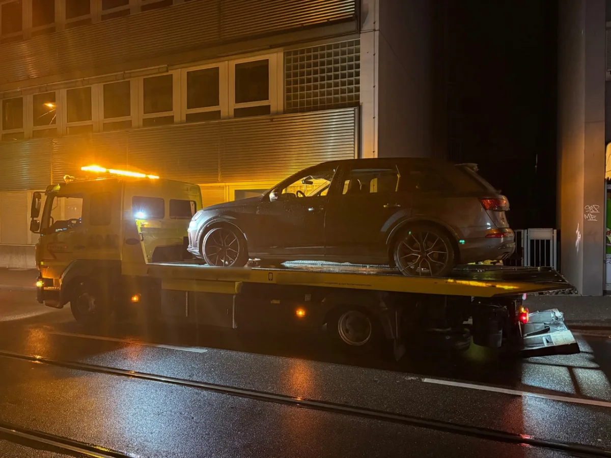 Ein dunkler SUV steht auf einem Abschleppwagen. Es ist Nacht, die Szene ist durch die Lichter des Wagens beleuchtet.