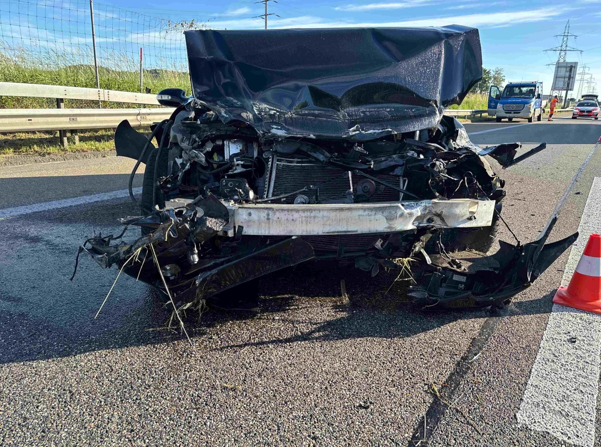 Ein stark beschädigtes Auto steht auf einer Straße, die Front ist stark deformiert. Im Hintergrund sind weitere Fahrzeuge zu sehen.