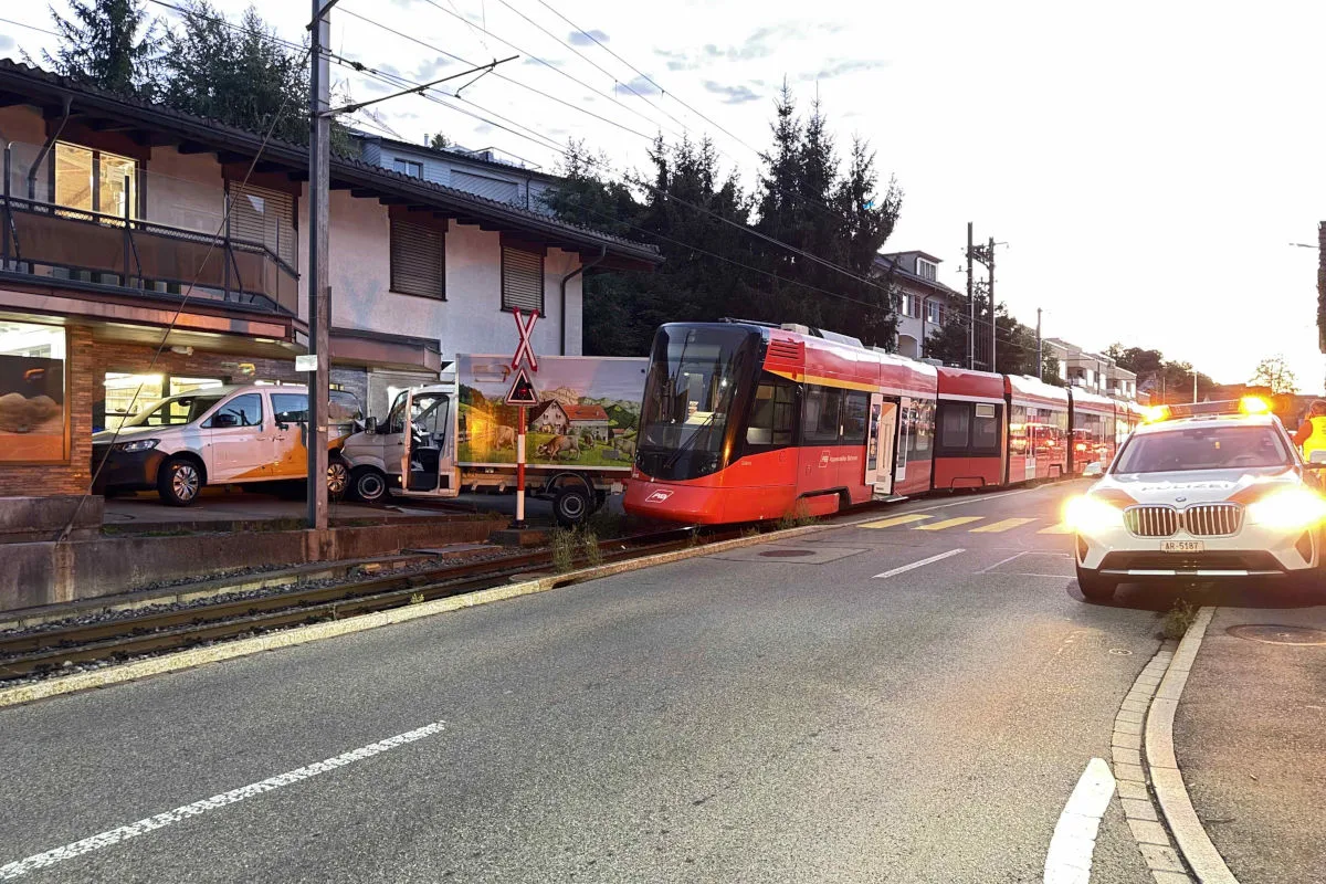 Ein rotes Tram steht auf Schienen, nachdem es mit einem bemalten Transporter kollidierte. Ein Polizeiauto ist am Unfallort.