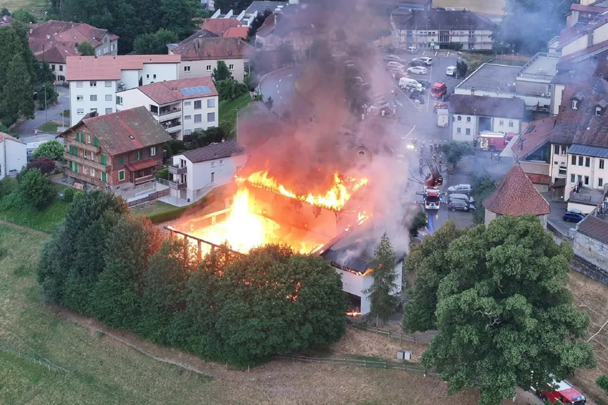 Ein Gebäude mitten in einem Wohnviertel steht in Flammen, während Feuerwehrfahrzeuge versuchen, das Feuer zu löschen.