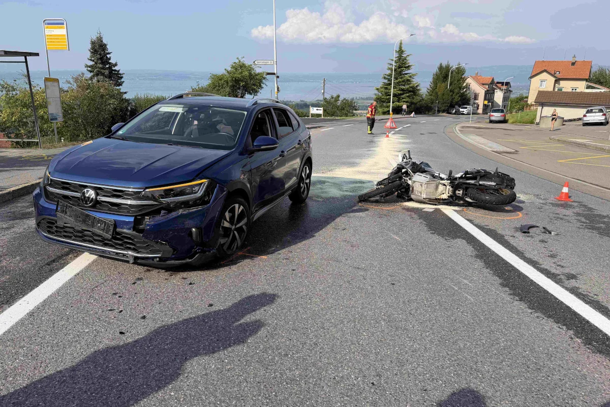 Ein Volkswagen steht beschädigt auf einer Straße, neben einem umgestürzten Motorrad. Im Hintergrund ein Rettungsmitarbeiter.