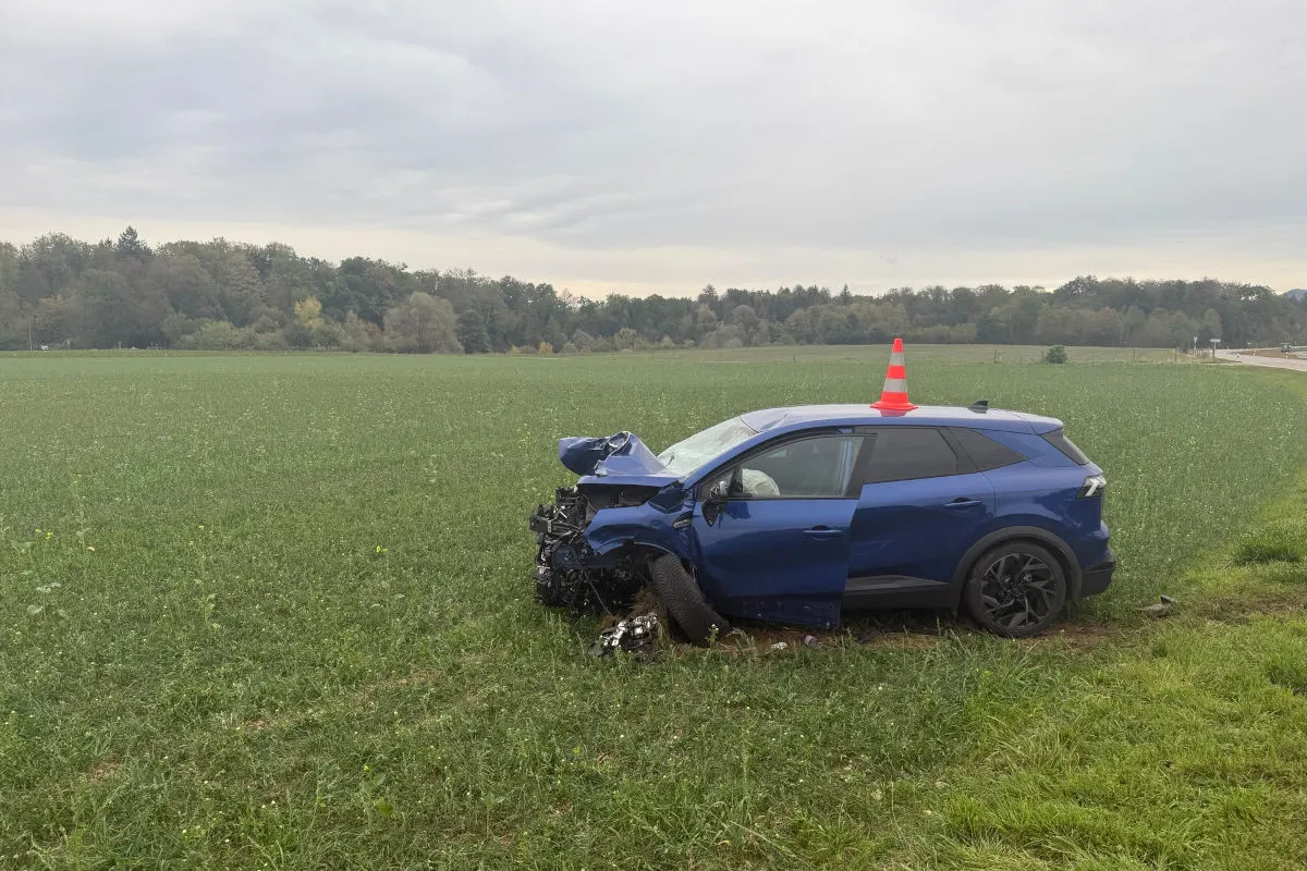 Ein blaues Auto mit starkem Frontschaden steht auf einem grünen Feld, eine rot-weiße Hütchenmarkierung auf dem Dach.