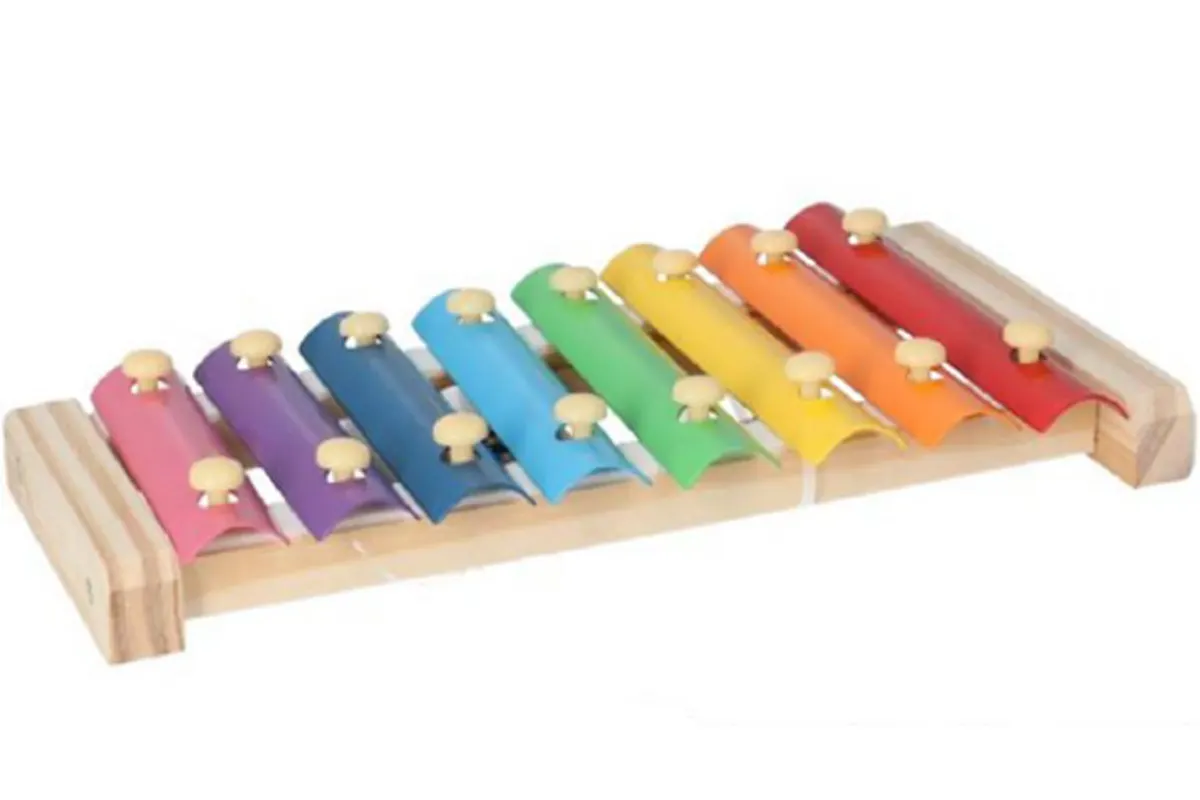 Ein Xylophon aus Holz mit farbigen Metallplättchen in Regenbogenfarben, auf einer weißen Fläche liegend.