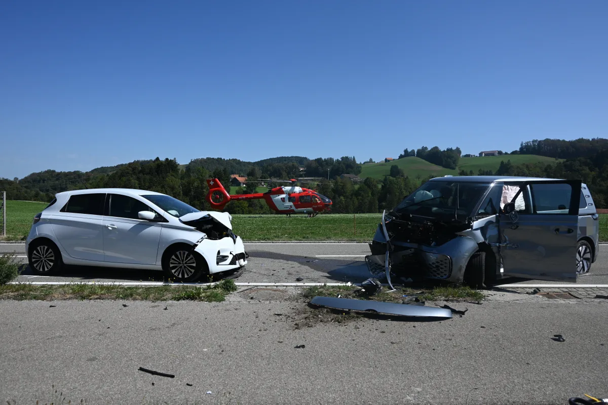 Auf einer Landstraße sind zwei beschädigte Fahrzeuge zu sehen. Im Hintergrund ist ein Rettungshubschrauber zur Unterstützung gelandet.