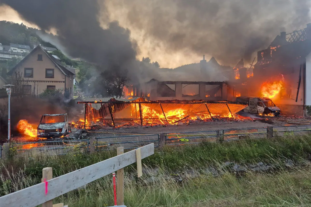 Ein massives Feuer zerstört mehrere Gebäude in einem Wohngebiet. Dichte Rauchschwaden steigen in den Himmel.