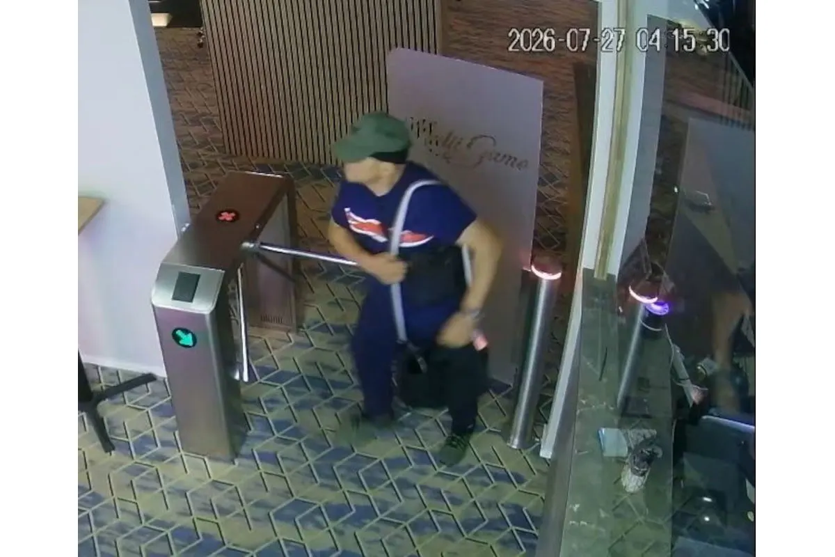 Ein Mann mit einem Rucksack und einer Mütze geht durch ein Drehtor in einem Innenraum. Die Aufnahme zeigt Fliesenboden und gläserne Wände.
