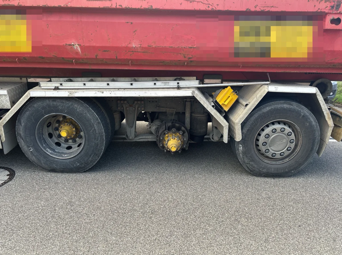Das Bild zeigt die Hinterräder eines Lastwagens. Eines der Räder fehlt, und der Achsbolzen ist sichtbar.