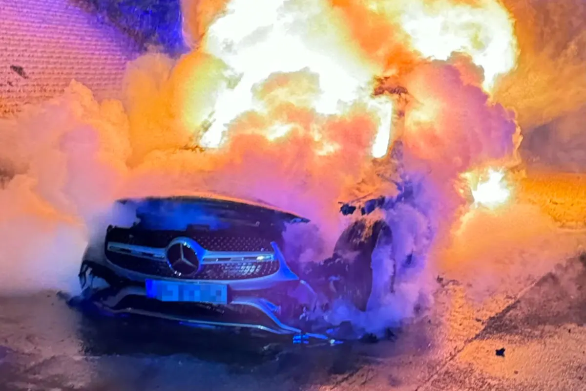 Ein Auto ist von Flammen und starkem Rauch umgeben. Das Fahrzeug scheint ein Mercedes zu sein.