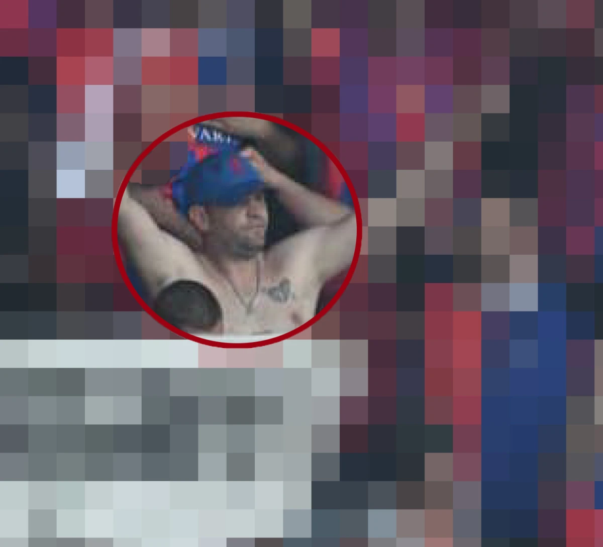 Ein Mann im Stadion ohne Hemd, mit einer blauen Kappe und tätowierter Brust, hebt die Hände hinter den Kopf.