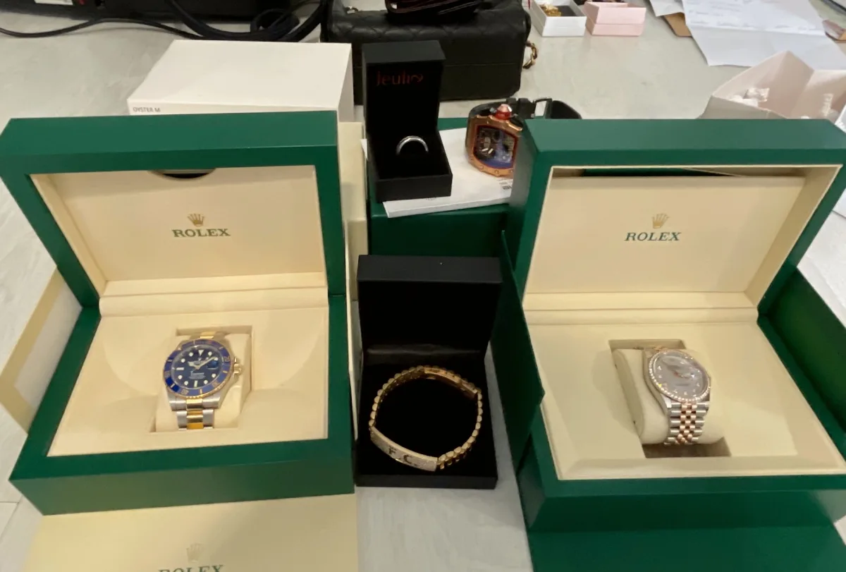 Im Bild sind zwei Rolex-Uhren in geöffneten grünen Schatullen zu sehen. Zusätzlich ist weiterer Schmuck wie Armbänder und Ringe in Schmuckverpackungen im Hintergrund erkennbar.