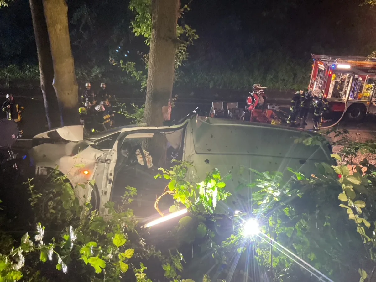 Ein weißer Transporter ist nachts im Wald verunglückt. Feuerwehrleute stehen in der Nähe, während ein Einsatzfahrzeug mit Beleuchtung vor Ort ist.